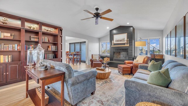 living room with lofted ceiling, a fireplace, light wood-type flooring, and ceiling fan