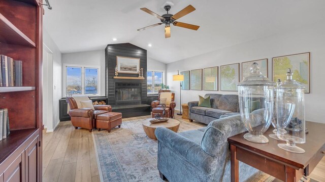 living room featuring lofted ceiling, a large fireplace, light hardwood / wood-style floors, and a healthy amount of sunlight