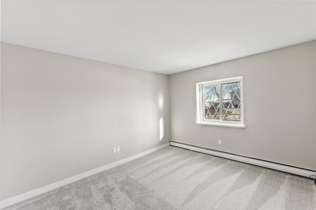 spare room featuring light carpet and a baseboard heating unit