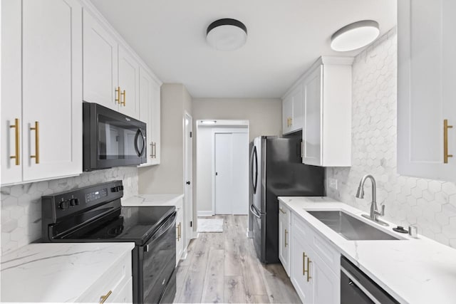 kitchen featuring black appliances, light wood-type flooring, light stone countertops, sink, and white cabinetry