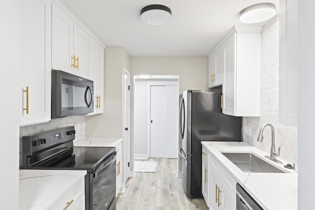 kitchen with light stone countertops, black appliances, tasteful backsplash, white cabinets, and sink