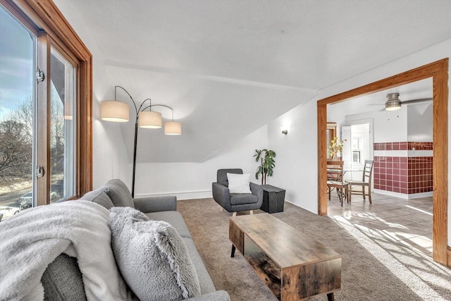 carpeted living room with ceiling fan and vaulted ceiling