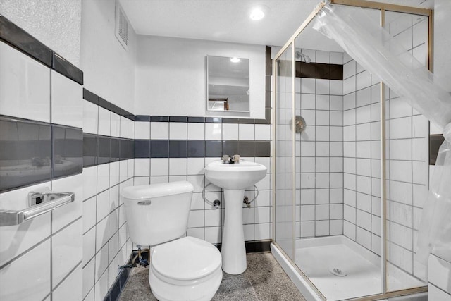 bathroom featuring tile walls, an enclosed shower, toilet, and sink