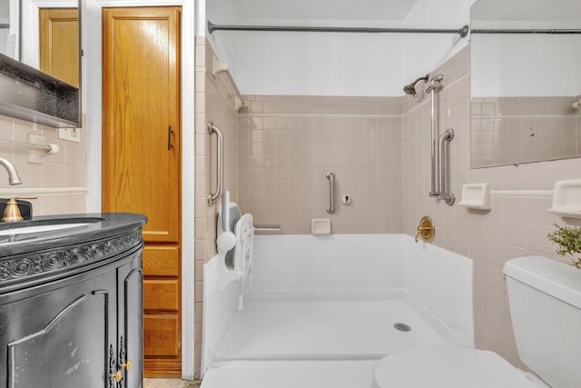 bathroom with toilet, tiled shower, decorative backsplash, tile walls, and vanity