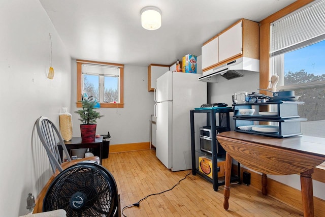 kitchen featuring white cabinetry, a healthy amount of sunlight, white refrigerator, pendant lighting, and light hardwood / wood-style flooring