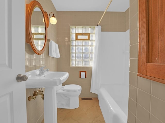 bathroom featuring toilet, tile walls, and shower / bath combo with shower curtain