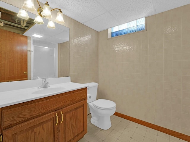 bathroom with a paneled ceiling, vanity, and toilet