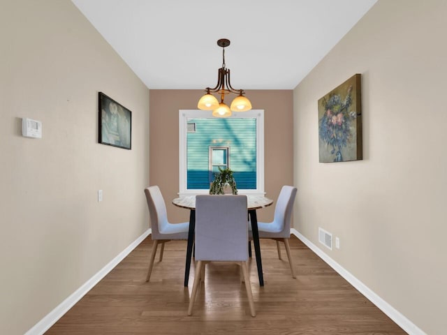 dining room with dark hardwood / wood-style flooring and a notable chandelier