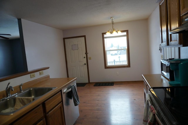 kitchen with hardwood / wood-style flooring, hanging light fixtures, stainless steel appliances, a notable chandelier, and sink