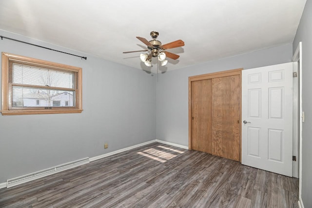 unfurnished bedroom with ceiling fan, baseboard heating, a closet, and dark wood-type flooring