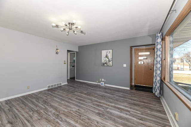 spare room with dark wood-type flooring and a chandelier