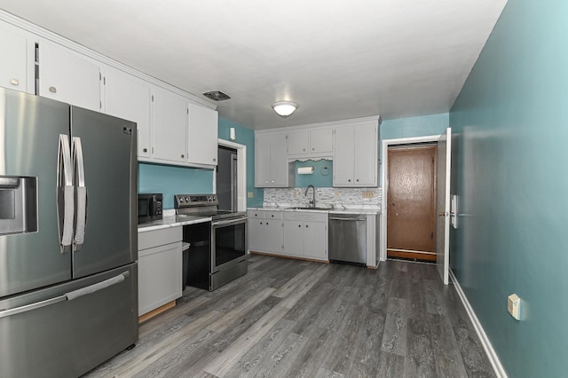 kitchen featuring appliances with stainless steel finishes, white cabinets, decorative backsplash, and sink