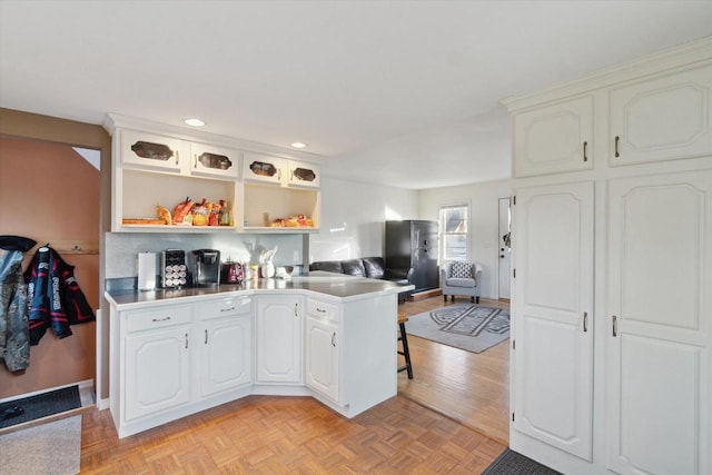 kitchen with white cabinetry, kitchen peninsula, and light parquet floors