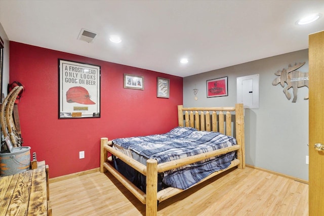 bedroom featuring electric panel and hardwood / wood-style flooring