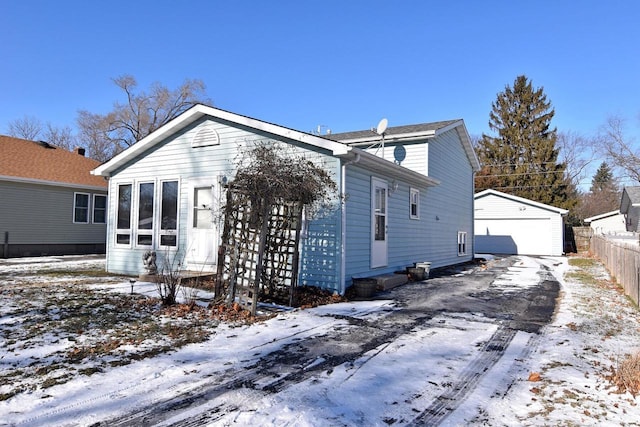 snow covered property featuring an outbuilding and a garage