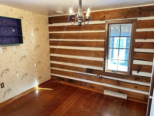 empty room with hardwood / wood-style flooring and a notable chandelier