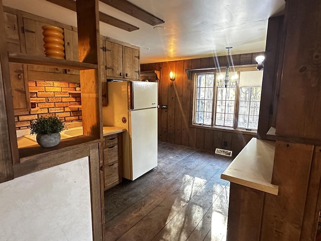 kitchen featuring wooden walls, an inviting chandelier, white fridge, dark hardwood / wood-style flooring, and pendant lighting