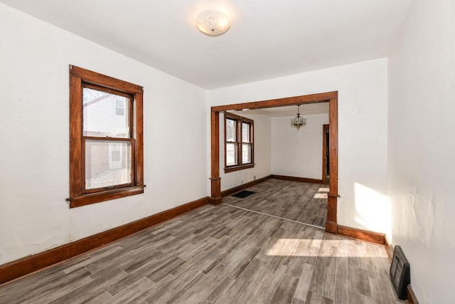 corridor with hardwood / wood-style floors, a healthy amount of sunlight, and a notable chandelier