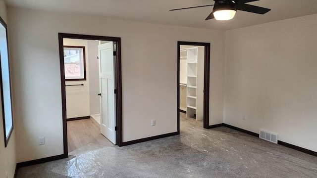 unfurnished bedroom with a walk in closet, ceiling fan, and a closet