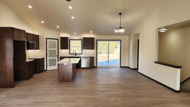 kitchen featuring decorative light fixtures, light wood-type flooring, appliances with stainless steel finishes, and a center island