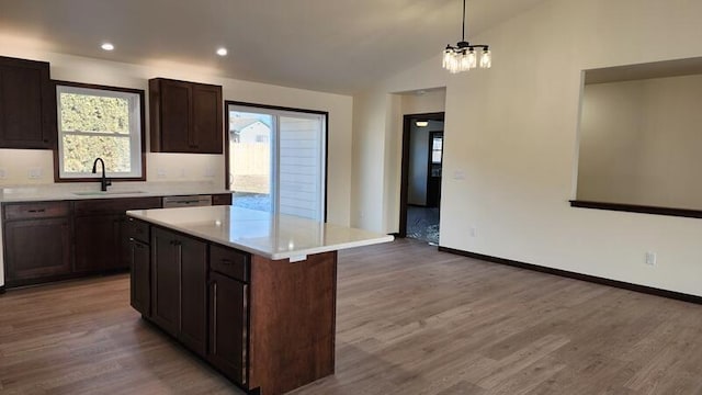 kitchen featuring sink, vaulted ceiling, hardwood / wood-style flooring, hanging light fixtures, and a kitchen island