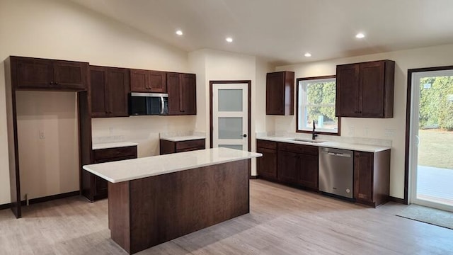 kitchen featuring vaulted ceiling, light hardwood / wood-style floors, stainless steel appliances, a kitchen island, and sink