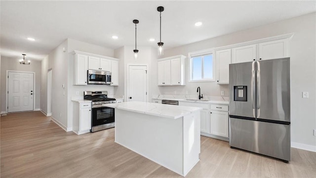 kitchen featuring a center island, decorative light fixtures, stainless steel appliances, white cabinets, and sink