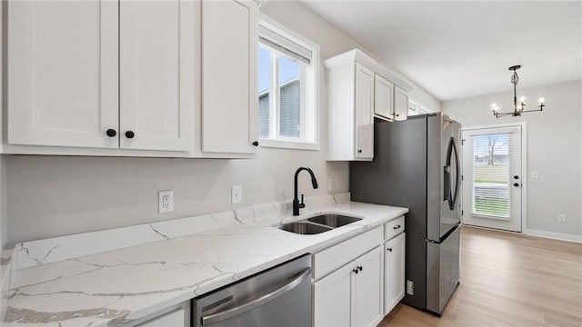 kitchen featuring stainless steel appliances, sink, an inviting chandelier, white cabinetry, and pendant lighting