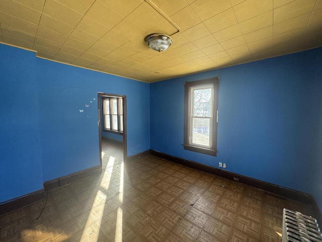 empty room featuring dark parquet flooring and radiator heating unit