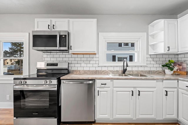 kitchen with white cabinets, appliances with stainless steel finishes, decorative backsplash, and sink