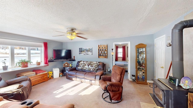 carpeted living room with a textured ceiling, ceiling fan, and a wood stove