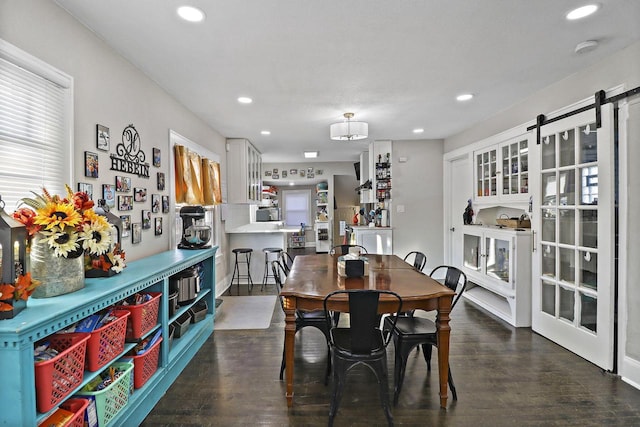 dining room with a barn door and dark hardwood / wood-style floors