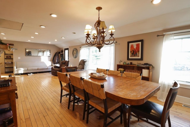 dining space with light hardwood / wood-style flooring, a wealth of natural light, and a chandelier