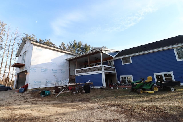 rear view of property featuring a balcony, ceiling fan, and a garage