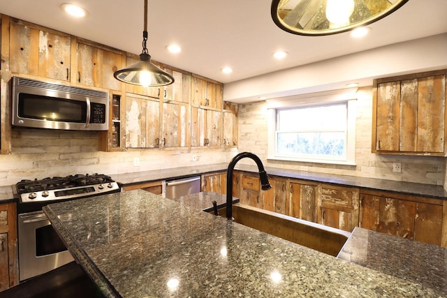 kitchen with decorative light fixtures, decorative backsplash, dark stone counters, appliances with stainless steel finishes, and sink