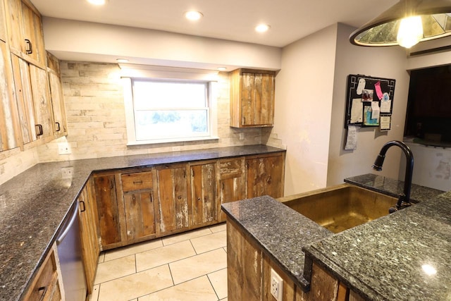 kitchen featuring dishwasher, backsplash, dark stone countertops, sink, and light tile patterned flooring