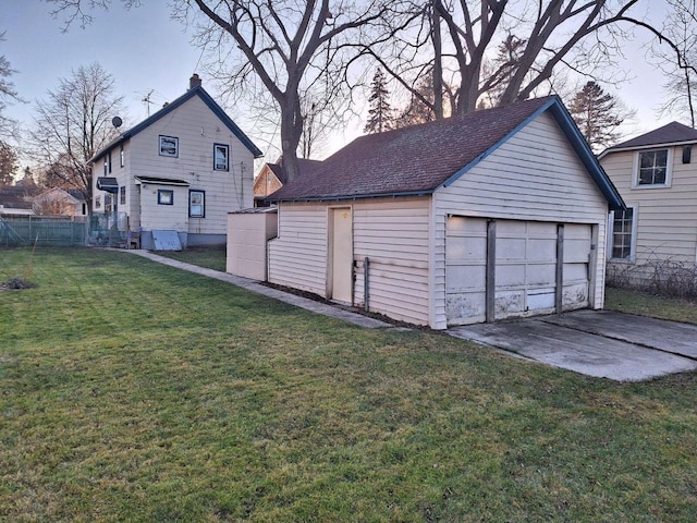 garage at dusk featuring a lawn