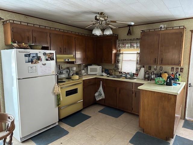 kitchen featuring sink, white appliances, ceiling fan, kitchen peninsula, and dark brown cabinetry