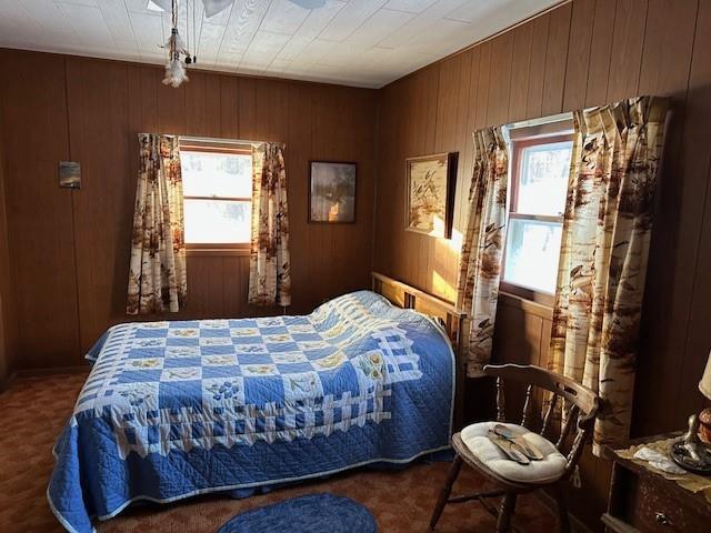 bedroom with wood walls and dark carpet