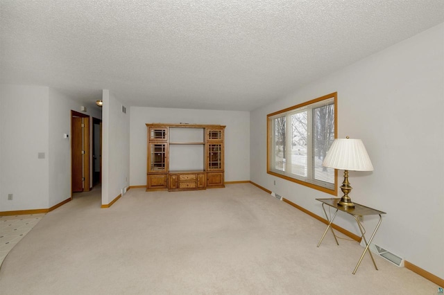 unfurnished living room featuring a textured ceiling and light carpet