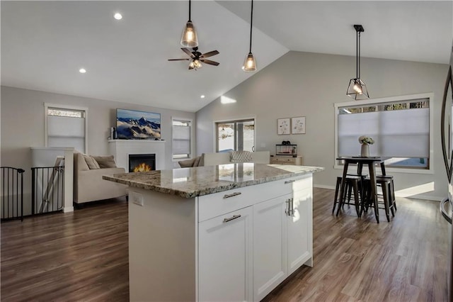 kitchen featuring white cabinets, a center island, decorative light fixtures, and light stone countertops