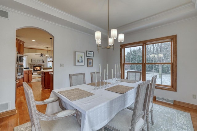 dining space featuring ornamental molding, ceiling fan with notable chandelier, and light hardwood / wood-style flooring