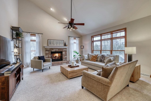 living room with ceiling fan, light colored carpet, a fireplace, and high vaulted ceiling