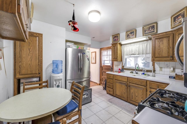 kitchen featuring sink, backsplash, stainless steel appliances, and light tile patterned floors