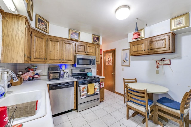 kitchen with light tile patterned flooring, appliances with stainless steel finishes, sink, and backsplash