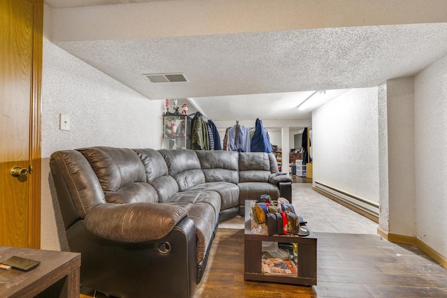 living room featuring dark wood-type flooring, a textured ceiling, and a baseboard heating unit