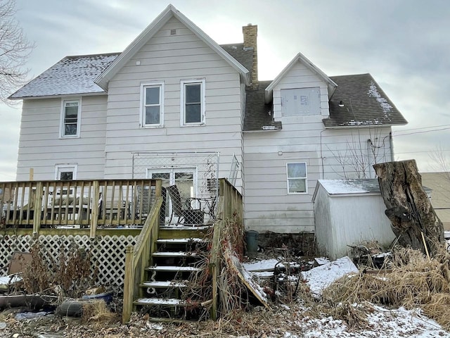 snow covered back of property with a deck