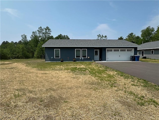 10004 Aspen Ln, Hayward, WI 54843 - single story home featuring an attached garage, asphalt driveway, a front lawn, and roof with shingles
