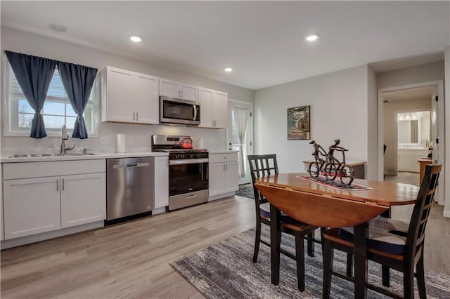 kitchen featuring stainless steel appliances, light wood-type flooring, white cabinets, and sink