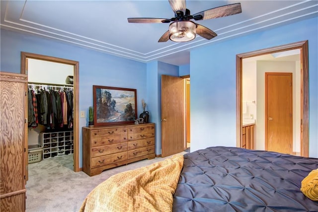 bedroom featuring a closet, ensuite bath, light colored carpet, ceiling fan, and a spacious closet